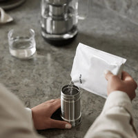 Refilling the Aarke Water Purifier Jug cartridge with ReFilter granules on a kitchen counter