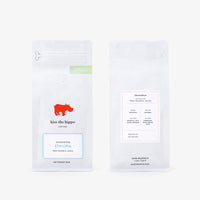Two white coffee bag packages shown side by side on a light gray background. The left package shows the front with a red hippo logo, the text 'kiss the hippo coffee,' and a blue-bordered label reading 'Jazmin Honduras.