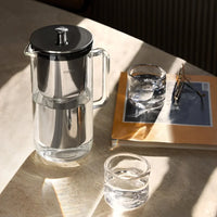 Aarke Water Purifier Jug on a sunlit table beside a glass of filtered water