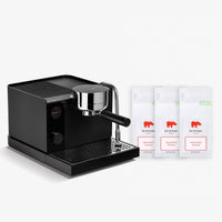 A black semi-automatic espresso machine with a chrome portafilter, shown next to three white coffee bean bags labeled 'koe de hopper' on a clean white background.