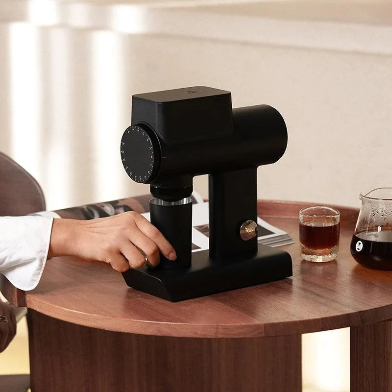 Hand positioning a dosing cup beneath a Timemore Sculptor in black