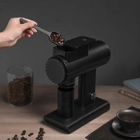 Pouring coffee beans into the hopper of a Timemore Sculptor in black