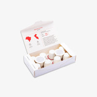 An open white cardboard box containing multiple small white cups, photographed on a clean light grey background. The inside lid has printed text and red map-style graphics.