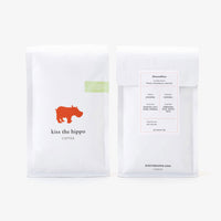 Two coffee packages from 'Kiss the Hippo' on a white background